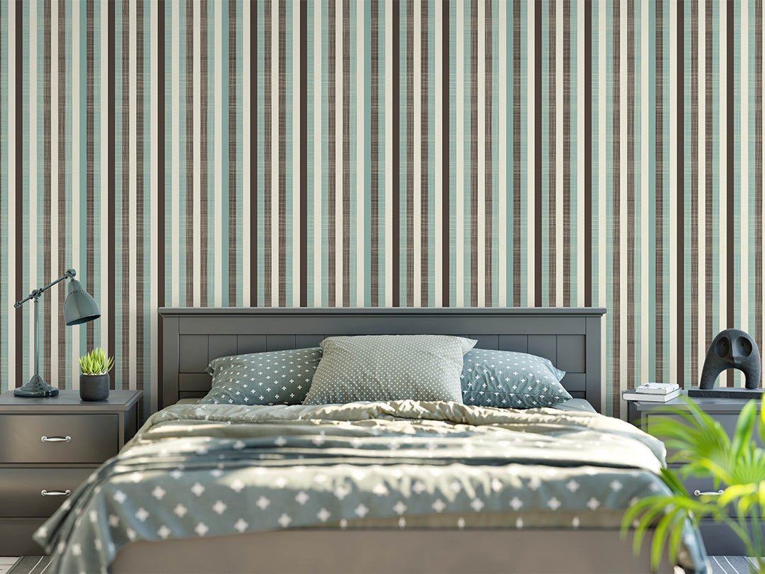 Vertical striped wallpaper in teal, brown and cream behind a gray wood bed with patterned bedding and bedside tables