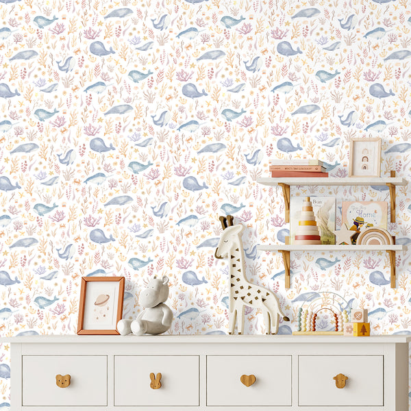 Blue whale underwater wallpaper featuring watercolor coral, starfish, seashells, fish, and sea plants in soft blue, peach, and sandy beige.