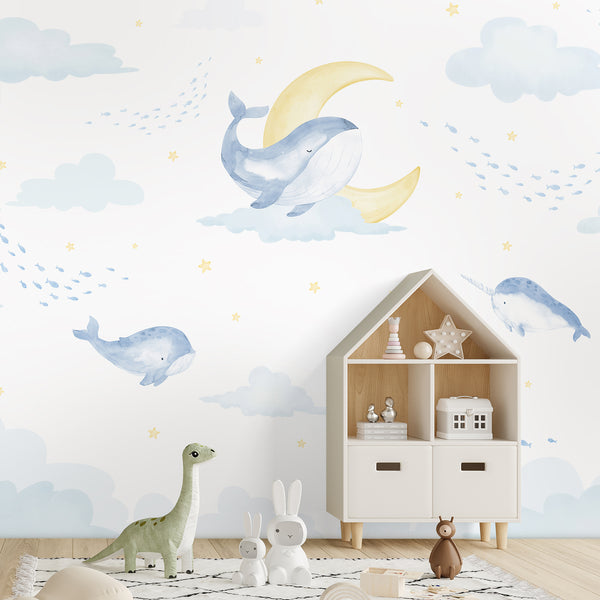 Whimsical whale wallpaper featuring blue watercolor whales, a narwhal, schools of tiny fish, soft clouds and golden yellow celestial accents.