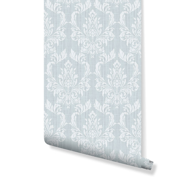 Blue Damask wallpaper showcasing soft white floral motifs on a pale blue background with a linen-like texture. Perfect for traditional living rooms or romantic bedrooms, this pre-pasted wallpaper brings vintage charm with its elegant, medium-large repeat pattern. Easy to apply, ideal for decorators looking to add classic elegance with eco-friendly materials.