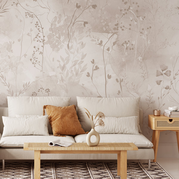 Watercolor botanical wallpaper featuring fine branches, leaves and wildflowers in light beige and warm taupe tones over a softly textured neutral background.
