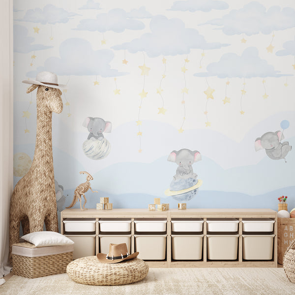 Gentle watercolor baby elephants mural with soft clouds and star garlands brings a calm feel to kids' bedrooms. This traditional unpasted wallpaper is eco-friendly and Made in the USA, providing a charming, temporary decor option that complements Scandinavian nursery themes.