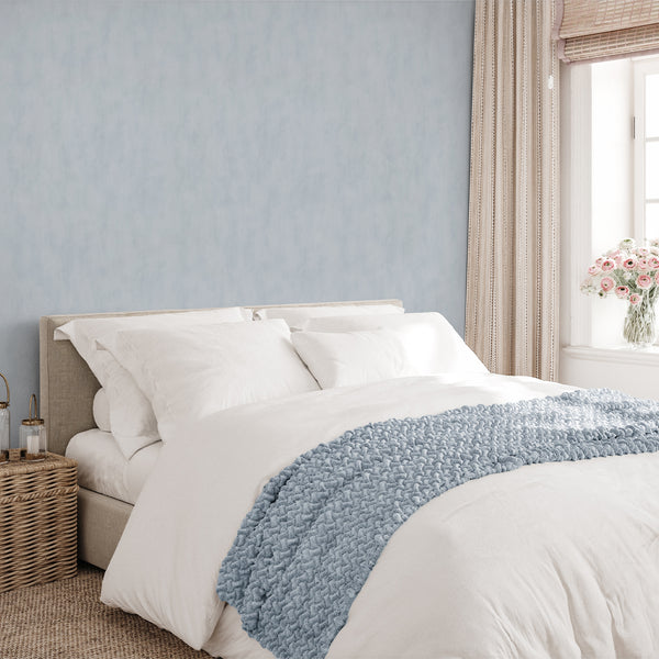 Pale blue plaster effect wallpaper with delicate tonal variation, providing a serene and understated depth for bedrooms or living rooms.