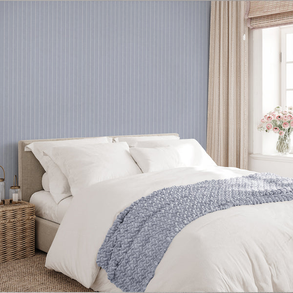 Modern geometric wallpaper in muted dusty blue with repeating white elongated diamond-like ovals forming decorative vertical stripes across the surface.