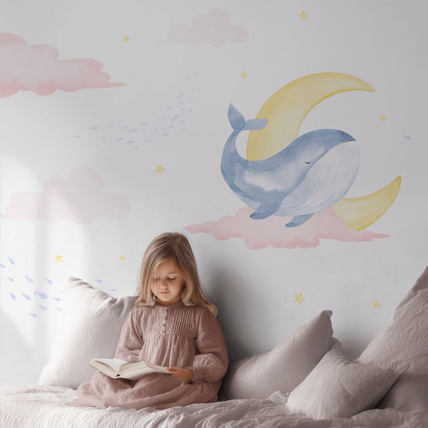 Watercolor nursery wallpaper with blue whales swimming among dreamy pink clouds, pale yellow moon, tiny stars and schools of light blue fish.