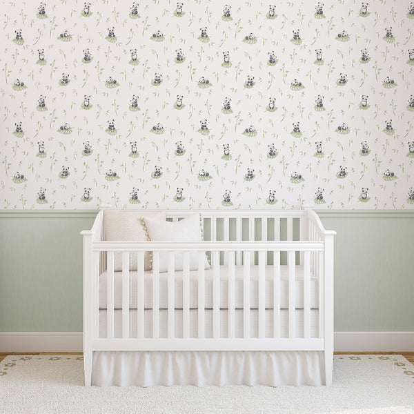 Black and white panda wallpaper with subtle pink cheeks and light green watercolor leaves, creating a playful botanical design for a nursery or kids room.