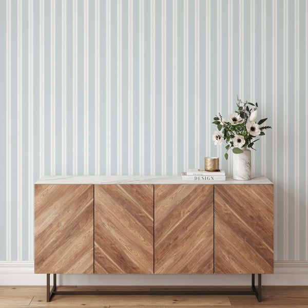 Coastal wallpaper in soft light blue and white with refined vertical stripes, creating an airy design for nurseries, bedrooms, and elegant interiors.