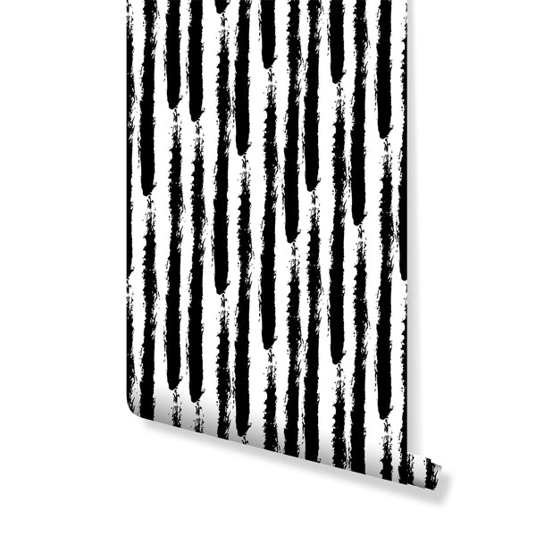Black & White Stroke wallpaper featuring irregular hand-painted black brushstrokes on crisp white. The high-contrast vertical stripes create a modern raw energy, perfect as a removable peel and stick accent wall in home offices or bold living rooms. Eco-friendly and Made in the USA, ideal for decorators.