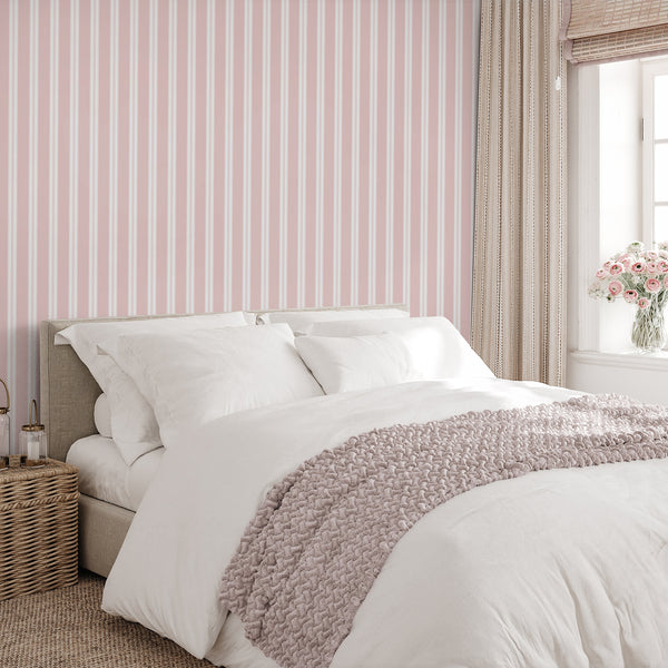 Removable wallpaper in blush pink and white with alternating broad stripes and narrow pinstripe details for a modern bedroom accent wall.
