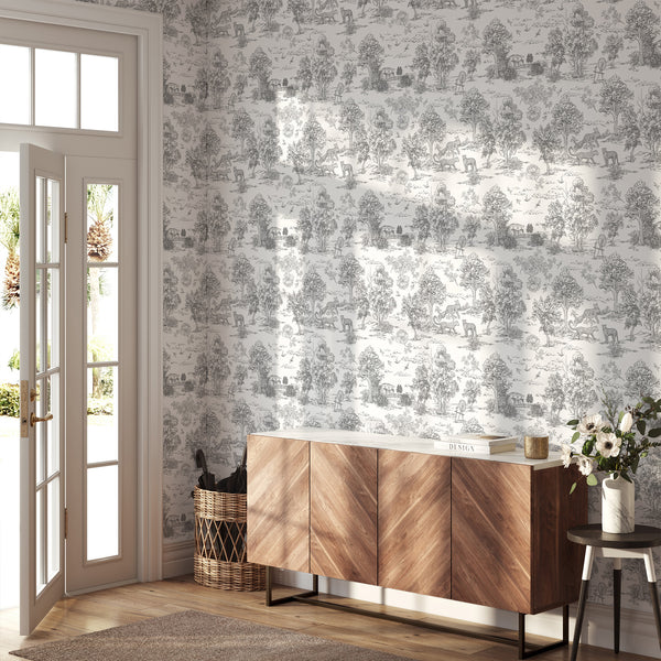 Gray toile safari wallpaper with scenic vignettes, ideal for creating a sophisticated statement in traditional or eclectic interiors. The self-adhesive wallpaper's mid-gray motifs on a white ground enhance the elegance of bedrooms or dining rooms.