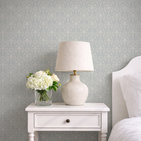 Cottagecore floral damask wallpaper with oversized ivory blossoms, decorative leaves and graceful botanical stems on a muted light blue background.