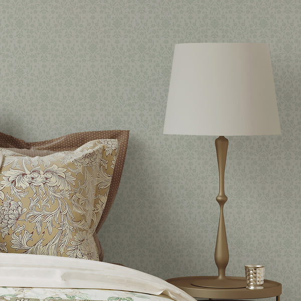 Light sage green and cream damask wallpaper featuring a repeating botanical vine design with a woven texture effect for a cozy bedroom or living room accent wall.