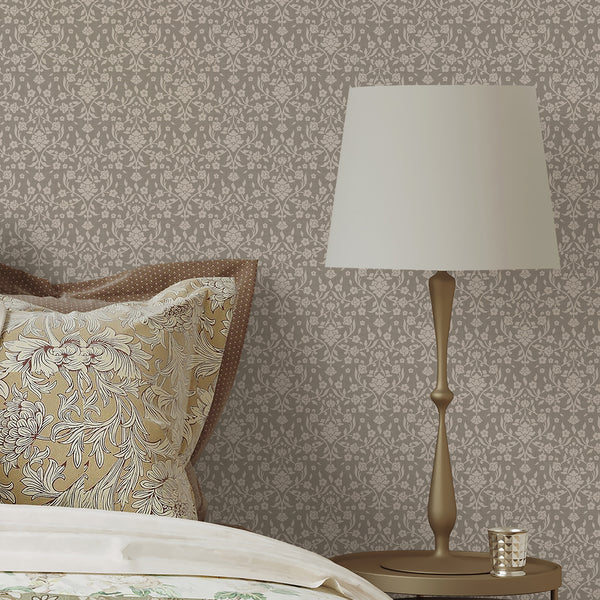 Vintage damask wallpaper featuring cream floral silhouettes, winding stems and botanical leaves against a warm beige taupe textured background.