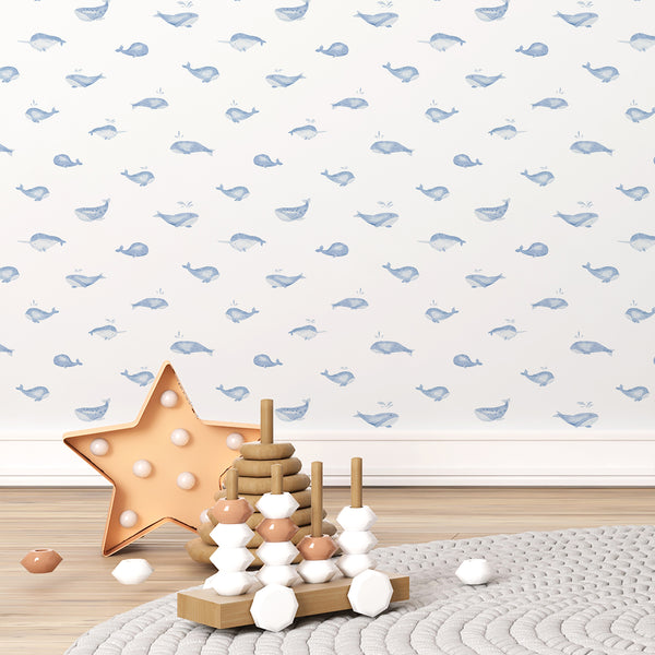 Soft blue whale wallpaper featuring a gentle watercolor whale with water splashes on a clean white background for an ocean-themed nursery.