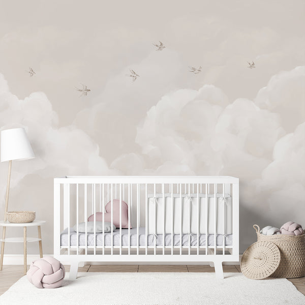 Neutral beige wallpaper featuring airy white clouds and small flying birds in a soft watercolor style, ideal for a minimalist nursery or bedroom.