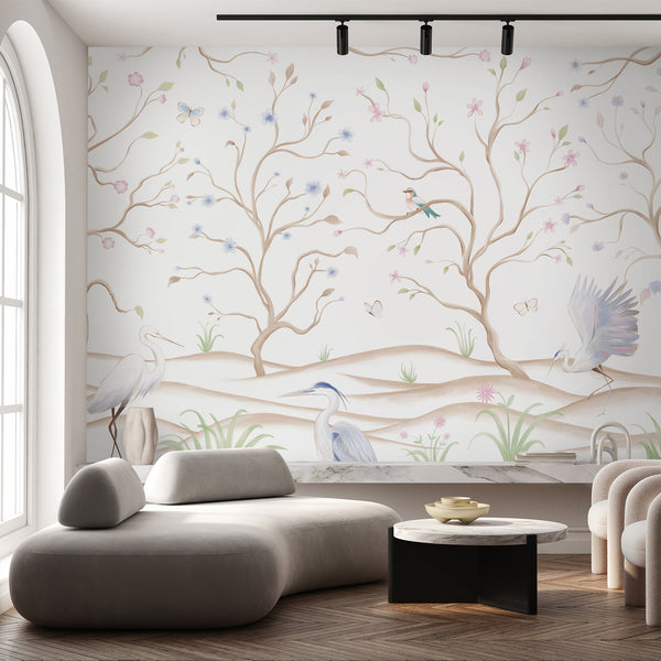 Heron bird wall mural featuring white wading birds, soft pink and blue blossoms, winding beige branches and butterflies on white.