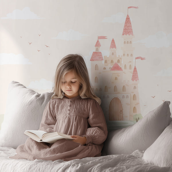 Magical kingdom wallpaper with a storybook princess castle, pink rooftops, soft pastel hills, tiny trees and clouds for a girls room or playroom.
