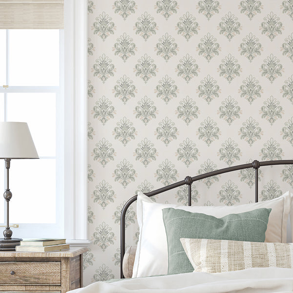 Sage green damask wallpaper with elegant ornamental scrollwork and soft beige accents on an ivory background, ideal for a vintage bedroom accent wall.