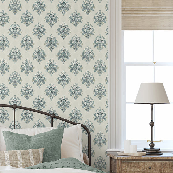 Ornamental damask wallpaper with intricate floral scrolls, vintage-inspired decorative shapes and muted dusty blue tones against a light cream background.