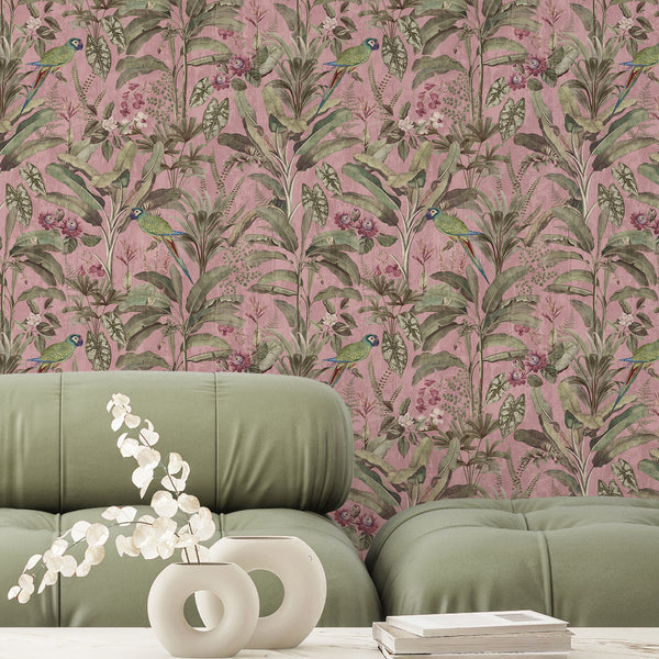 Tropical bird wallpaper with green parrots, pink orchids and dense botanical foliage against a textured dusty pink background for an eclectic interior.