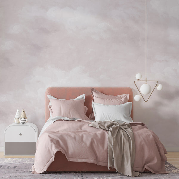 Dusty pink removable wallpaper with airy white clouds and a soft watercolor sky design, perfect for a nursery, bedroom, or kids room accent wall.