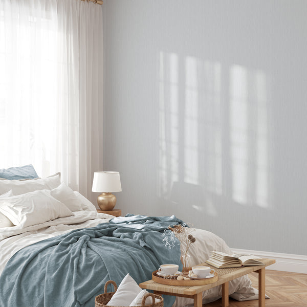 Close-up of the Light Blue Vertical Texture Wallpaper showing irregular thin lines on a soft blue-gray background. The design resembles airy linen, offering a calming, low-contrast look suitable for small hallways or renter-friendly bedrooms. Made in the USA with high-quality removable material.