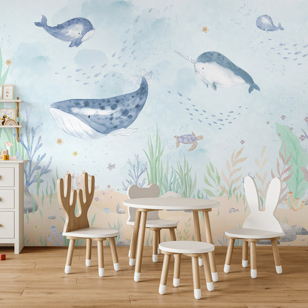 Watercolor underwater wallpaper with blue whales, a narwhal, sea turtle, schools of fish, coral, seaweed, and a soft sandy ocean floor.