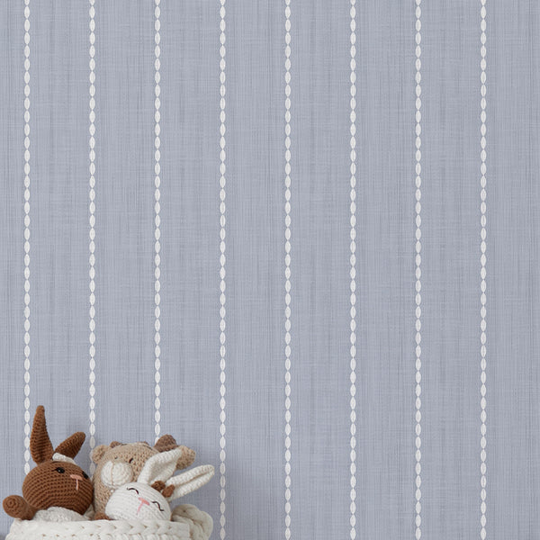 Textured blue wallpaper featuring narrow vertical rows of white oval shapes, softly faded blue gray tones, and a distressed finish for living room walls.