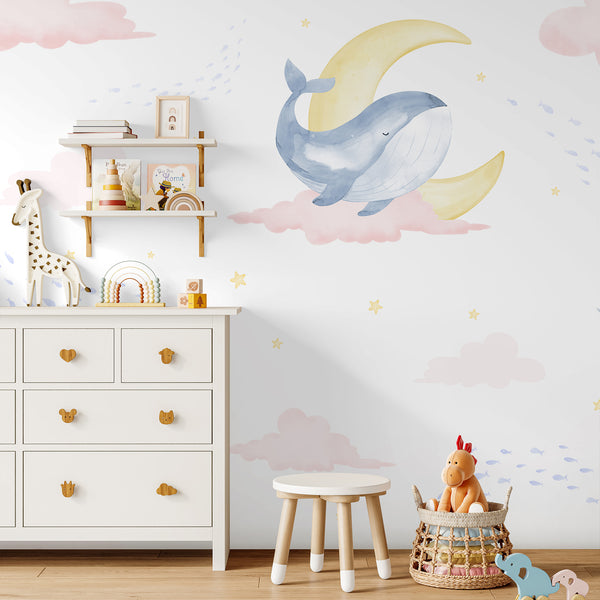 Pink cloud nursery wallpaper with blue whales, narwhal, tiny fish, crescent moons and golden yellow stars in a dreamy watercolor storybook style.