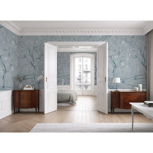 Light blue botanical wallpaper featuring elegant heron birds, flowering branches and watercolor foliage for a bedroom or living room wall.