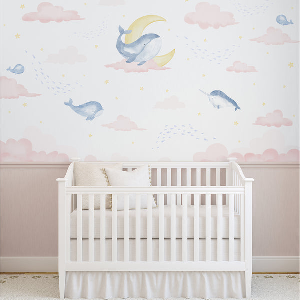 Pink and blue whale nursery wallpaper featuring watercolor whales, a narwhal, soft pink clouds, yellow crescent moon, stars and tiny fish.