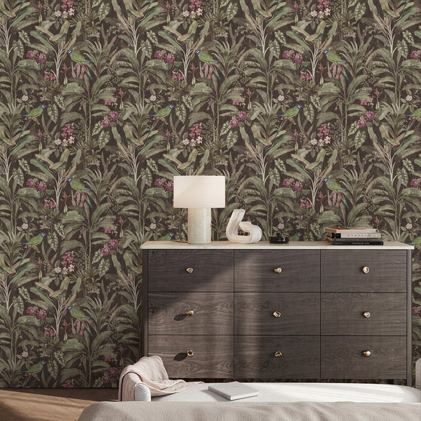 Dark jungle wallpaper with colorful parrots, green botanical leaves and pink floral accents designed for an eclectic bedroom or living room interior.