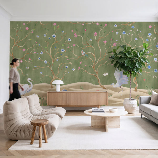Green floral wallpaper featuring elegant flowering trees, heron birds, butterflies and botanical details for a bedroom or living room wall.