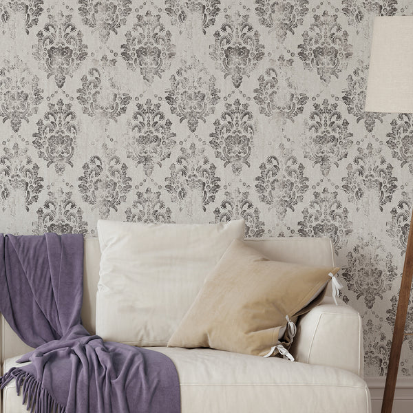 Warm gray damask wallpaper with ornate medallions and distressed charcoal tones, ideal for a living room or dining area. This traditional wallpaper offers a vintage, rubbed print effect, perfect for classic or French country decor.
