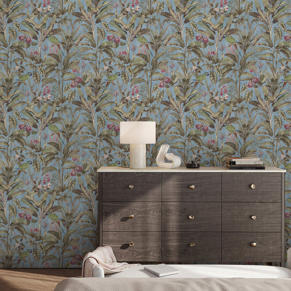 Dusty blue tropical wallpaper with green parrots, layered jungle foliage and muted floral accents for an elegant vintage-inspired interior.