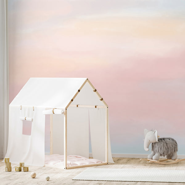 Soft pastel watercolor wallpaper featuring blended blush pink, pale blue, peach and cream tones with a dreamy abstract gradient for a nursery or bedroom.