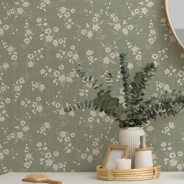 Sage Green Floral Wallpaper features fine stems and small clustered flowers over a dusty sage green ground. The subtle linen-like texture adds warmth and depth, making it suitable for creating a soft, inviting atmosphere in bedrooms or studies.