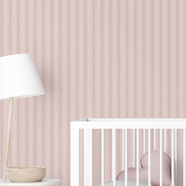 Soft pink nursery wallpaper with delicate white botanical flowers, repeating vertical bands, and warm rose accents for a charming girls room.