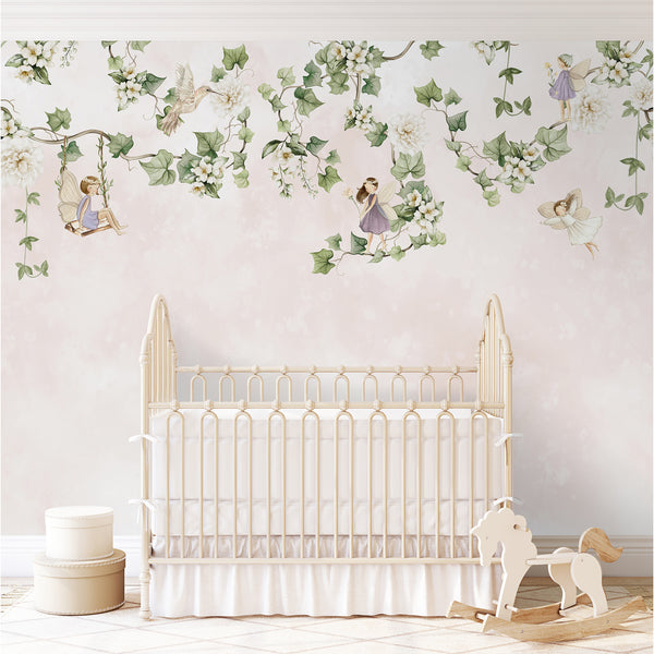 Fairies and hanging vines wall mural featuring delicate watercolor greenery and tiny fairies set against a blush pink background. Ideal for a nursery accent wall, offering self-adhesive and removable options.
