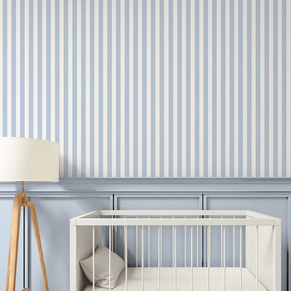 A styled nursery interior featuring light blue and white vertical striped wallpaper on the upper wall with a blue chair rail.