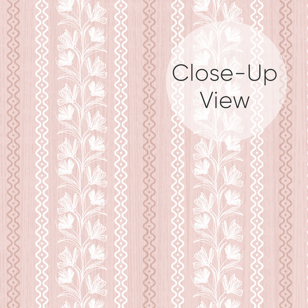 Close up of removable dusty pink wallpaper with vertical floral vines, white sketched blossoms, and wavy stripe details for a nursery or bedroom accent wall.