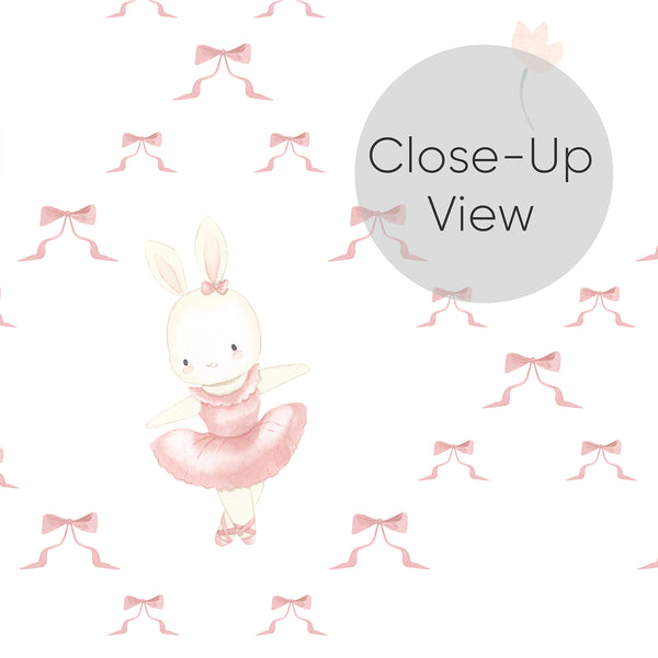 Close up of pink rabbit nursery wallpaper with a ballerina bunny in a soft tutu and scattered ribbon bows, creating a whimsical look. 