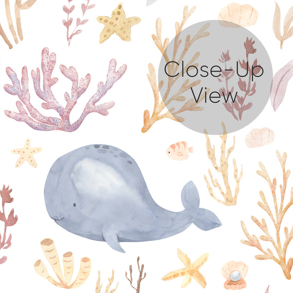 Close up of underwater sea life wallpaper featuring a gentle blue whale surrounded by pink coral, golden seaweed, shells, fish, and starfish for kids rooms.