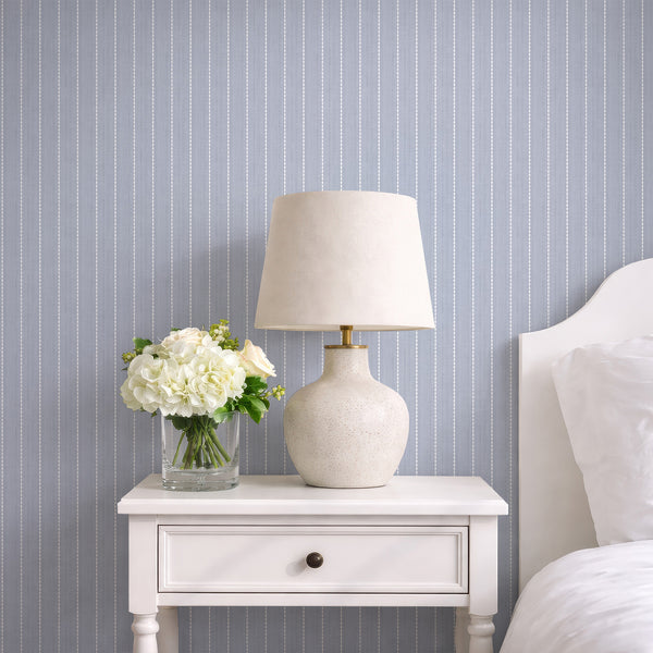 Dusty blue gray geometric wallpaper featuring vertical rows of elongated white oval shapes over a distressed textured background with a vintage-inspired finish.