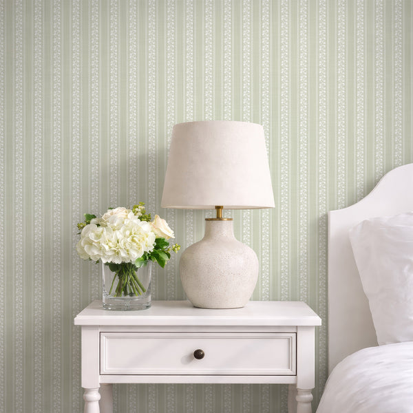 Sage green floral stripe wallpaper with white hand-drawn flowers, wavy scallop borders, and a soft textured background for a cottagecore nursery.