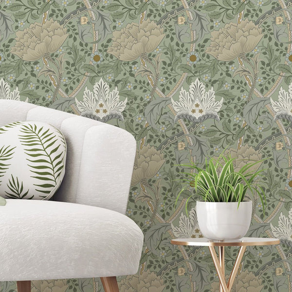 Green and beige Windrush wallpaper by Morris, featuring formal botanical patterns with stylized blooms and scrolling acanthus leaves. Ideal for living rooms or offices, offering a heritage-inspired flow with sage green and muted olive tones.