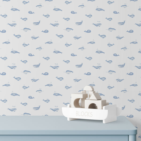 Baby boy nursery wallpaper with a pastel blue whale and playful water splashes, creating a charming coastal look for a kids bedroom.