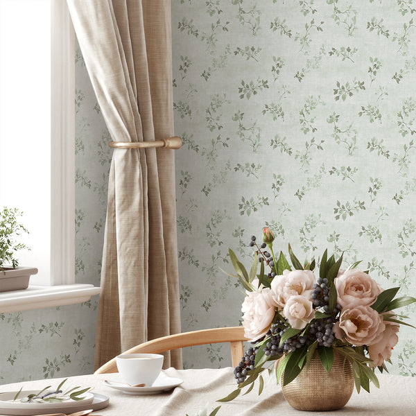 Green floral vine wallpaper with delicate sage green vine sprigs and leaf clusters on a pale, linen-effect ground. The petite scale creates a cozy, timeless look, perfect for bedrooms or dining rooms with a cottagecore theme. This removable peel and stick wallpaper is eco-friendly, made in the USA, and ideal for renters.