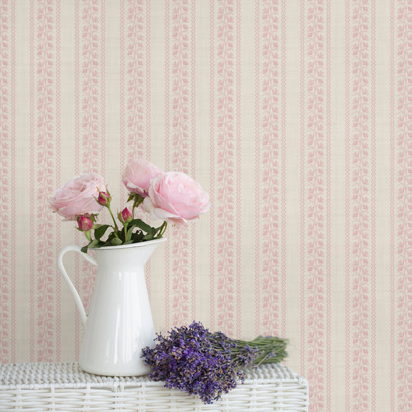 Blush pink floral stripe wallpaper with delicate botanical vines, decorative wavy borders, and a soft textured background for nursery or bedroom decor.
