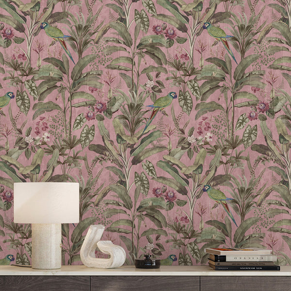 Pink tropical wallpaper featuring green parrots, muted floral details and lush botanical foliage in an elegant vintage jungle illustration style.